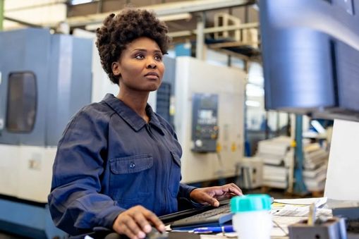Woman working on a computer in a warehouse - Applied CAx Siemens machining software