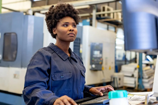 Woman working on a computer in a warehouse - Applied CAx Siemens machining software