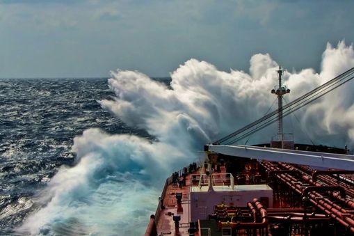 Large cargo ship cutting through open ocean with big wave hitting ship — Applied CAx Siemens maritime defense software