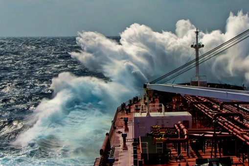 Large cargo ship cutting through open ocean with big wave hitting ship — Applied CAx Siemens maritime defense software